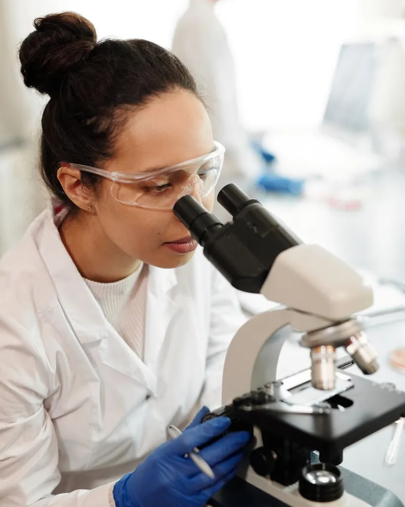 Biologa al microscopio in laboratorio