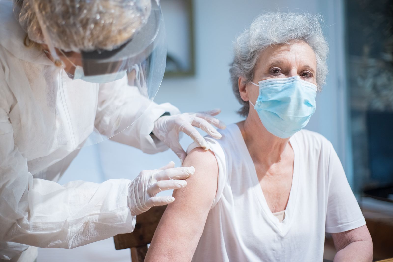 Infermiera che vaccina un paziente anziano